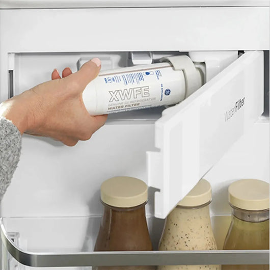 Hand replacing a water filter in a refrigerator with 'XWFE' branding.